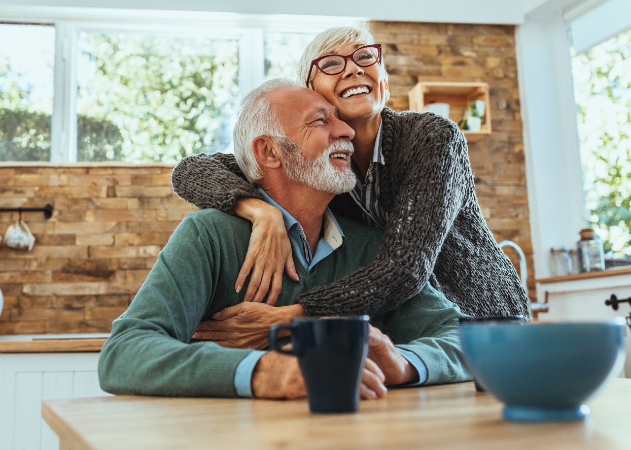 Mature couple hugging at table in kitchen
